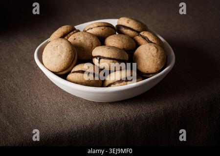 'Baci di dama', shot from the front to highlight their shape and the thin layer of chocolate cream that joins the two halves. Front view. Stock Photo
