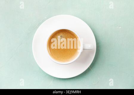Top view of a white cup of espresso on a saucer placed on a mint green textured background. Minimal coffee composition with soft pastel tones and copy Stock Photo