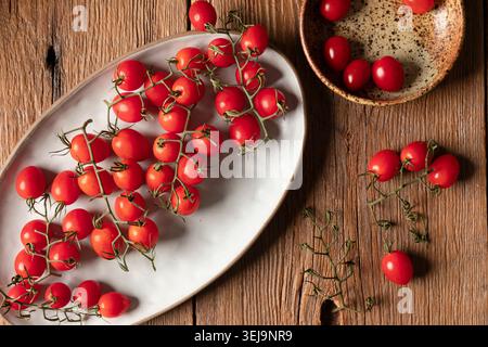 Grape tomatoes on the vine on rustic wooden surface Stock Photo
