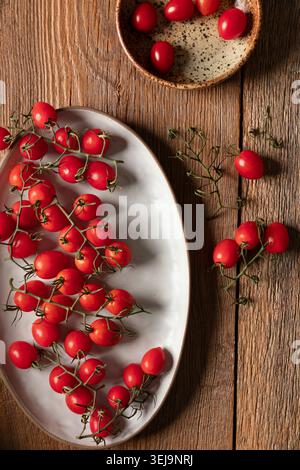 Grape tomatoes on the vine on rustic wooden surface Stock Photo
