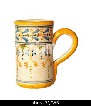Colorful hand painted ceramic mug isolated on white background showing traditional floral pattern with blue green and orange motifs and bright yellow Stock Photo