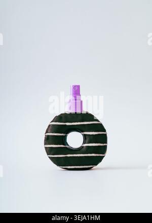 Creative sweet cosmetic and makeup concept with chocolate donut cosmetic spray on white background. Donut aesthetic. Stock Photo