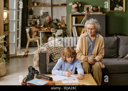 Senior Woman Watching Child Studying at Home for Family Learning Stock Photo