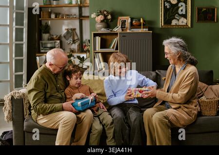 Senior Couple with Children Exchanging Gifts at Family Gathering Stock Photo