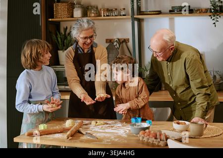 Senior Couple Baking with Children in Kitchen for Family Bonding Stock Photo