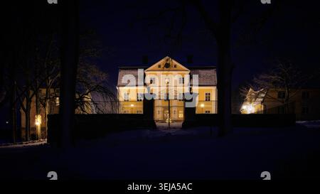 Fagervik, Finland - 26.12.2023: Illuminated traditional manor house in snowy landscape Stock Photo