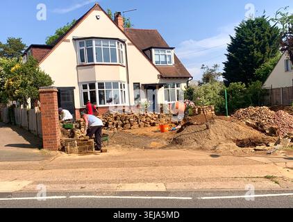 Builders at work on a sunny day preparing the front garden of a detached suburban house for new stonework and landscaping in Northampton England Stock Photo