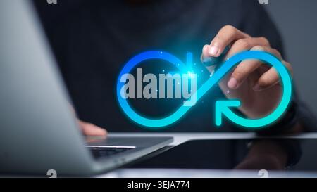 Businessman hand using stylus with glowing infinity loop arrow on virtual screen. Concept of circular economy, sustainability, continuous improvement, Stock Photo