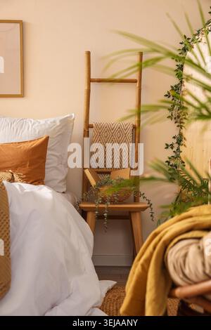 Table with books, plant and ladder in cozy bedroom Stock Photo