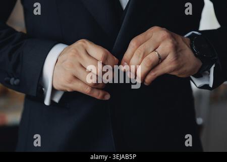 Man in dark suit buttons jacket with care Stock Photo
