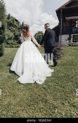 Young couple walks hand in hand through green grass Stock Photo