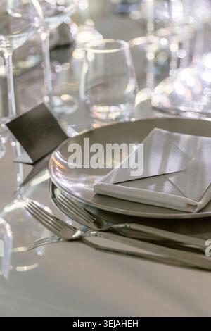 Elegant restaurant table setting with plates and crystal glasses in soft light Stock Photo