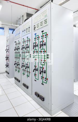 Clean interior view of an electrical switch gear room at a substation displaying mimic diagrams and control switches on main panels. Stock Photo
