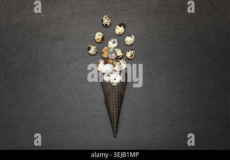 Dark waffle cone with easter eggs on a black background. Space for text. View from above. Flat lay Stock Photo