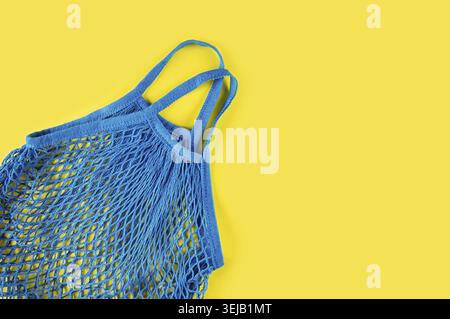 Blue reusable mesh on a yellow background. Ecological concept. Caring for the environment and rejection of plastic. Flat lay Stock Photo