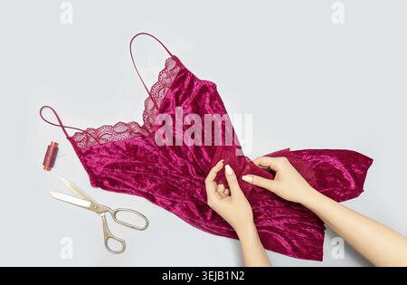 The process of manually sewing linen. Scissors, accessories for sewing. Lace in the hands of a tailor close-up. The apartment was lying. Copy space Stock Photo