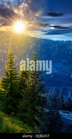landscape with coniferous forest behind the meadow. day meet night. sun and moon over nature background with carpathian mountains of ukraine. astrolog Stock Photo