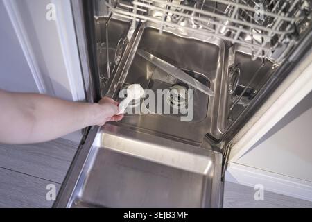 Person loading dishwasher with detergent in open kitchen appliance Stock Photo
