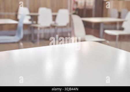 Empty modern cafeteria with white tables and chairs in soft focused background Stock Photo