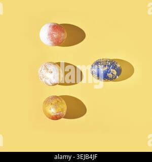 Four colorfully painted easter eggs on yellow background with shadows in artful composition Stock Photo
