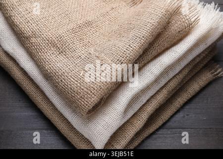 Folded natural burlap fabrics on wooden table, closeup Stock Photo