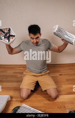 Vertical portrait of handyman frustrated assembling new office chair, feeling stressed by diy furniture instructions, struggling with home office Stock Photo