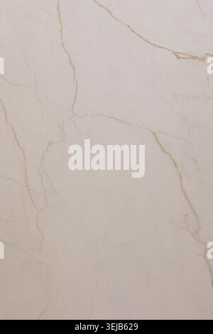 This smooth light beige marble surface showcases delicate golden veins, adding a touch of elegance to any contemporary design. Perfect for countertops Stock Photo