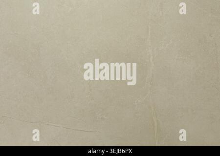 A light beige marble surface is displayed, featuring subtle veins and texture that reflect bright lighting. This natural stone adds elegance and sophi Stock Photo