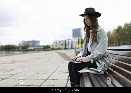Young strong woman freelancer software developer working on laptop outside Stock Photo
