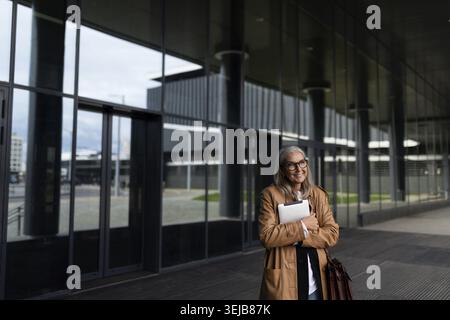 Business fifty-year-old woman with a tablet in her hands at the entrance to the business center Stock Photo