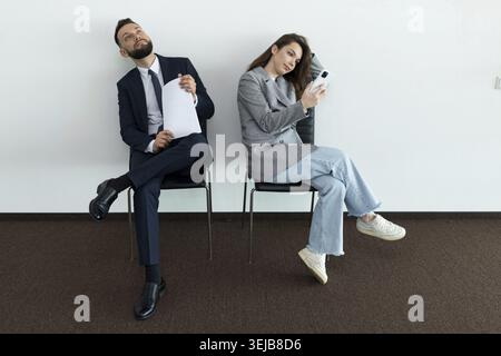 Office employees sit on chairs man and woman waiting for an interview Stock Photo