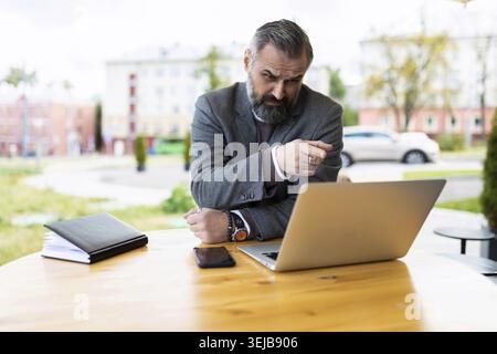 Fifty serious male businessman working on a laptop in a street cafe Stock Photo