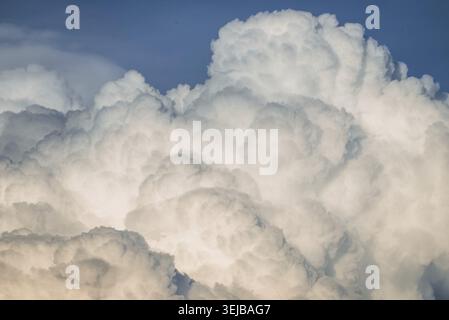 Bright white cumulus clouds filling the frame against a vibrant blue sky, creating a stunning and dramatic cloudscape on a sunny day, evoke a sense of Stock Photo