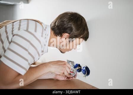 Electrician carefully installing electrical sockets in a new apartment, connecting wires using a screwdriver, demonstrating professionalism and precis Stock Photo