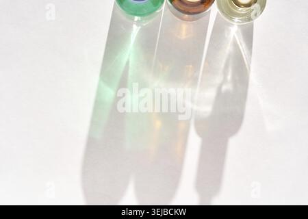 Colorful glass bottles casting shadows on white background in sunlight display artistic light and shadow Stock Photo