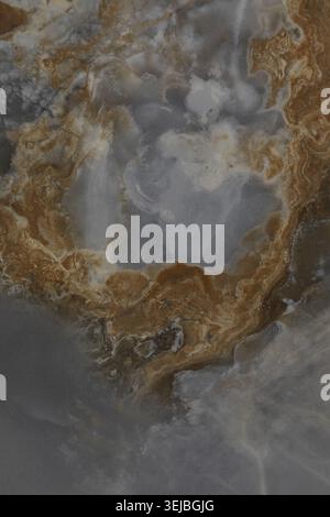 Swirling patterns of grey, brown, and white create a beautiful natural stone surface. The design mimics the movement of water and highlights unique fo Stock Photo