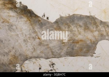 Close-up view of natural marble stone showcasing unique patterns and colors. The surface features stunning details with swirls of gray, white, and ora Stock Photo