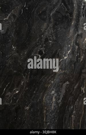 A close-up view of dark marble featuring striking white veining patterns. The surface reflects light, highlighting its elegant and sophisticated appea Stock Photo