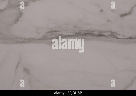 A close-up view reveals a white marble surface featuring delicate grey veins running through it. The smooth texture offers a sophisticated and timeles Stock Photo