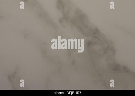 A close-up view highlights the smooth texture and subtle gray patterns of white marble. The surface reflects light, showcasing the stone's natural all Stock Photo