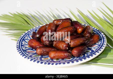 Fresh organic Tunisian dates served on decorative ceramic plate. Stock Photo