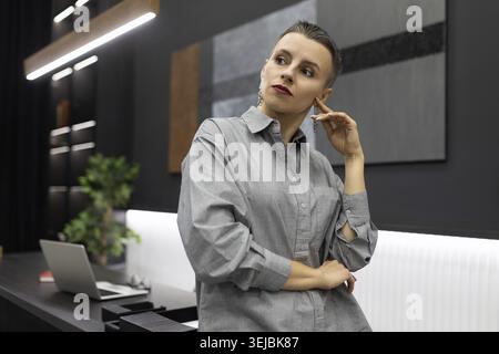 Confident modern woman head in a sterile office stands thinking Stock Photo