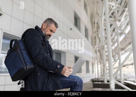 Businessman at the airport waiting to board the plane working online on a laptop Stock Photo