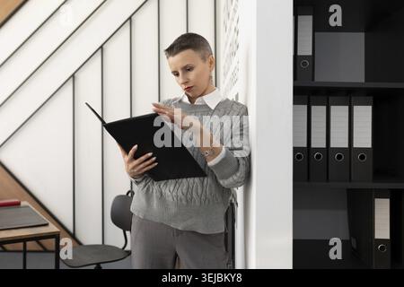 Office worker woman with a folder for papers stands in the office Stock Photo