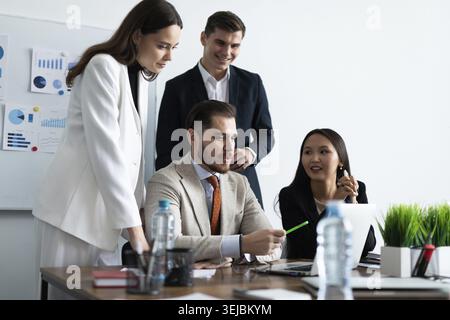 Smiling diverse colleagues gather in boardroom brainstorm discuss financial statistics together Stock Photo