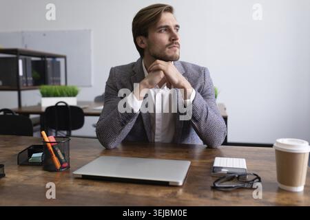 Mature serious businessman sitting at the table thoughtfully looking out the window Stock Photo