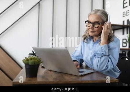 Caucasian businesswoman in headphones watching webinar on laptop in office Stock Photo