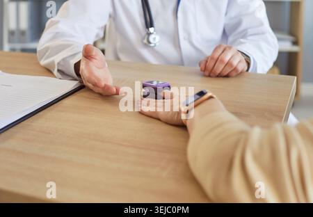 Doctor using electronic oximeter to measure peripheral blood oxygen saturation of patient Stock Photo