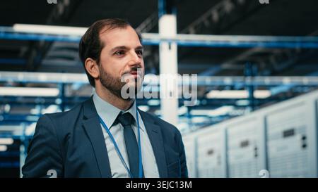Cheerful data center technician removing VR goggles after finishing equipment rigs optimization. Jolly server farm expert pleased after using virtual reality technology to upgrade hardware, camera B Stock Photo