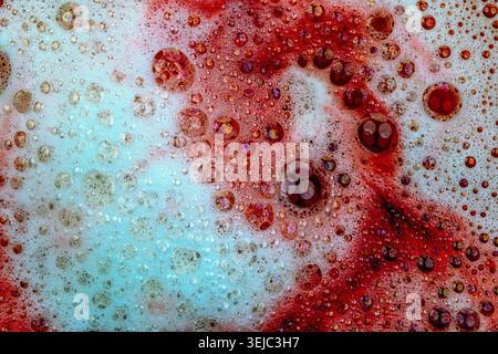 Detergent foam with bubbles and colored bubbles in red liquid Stock Photo